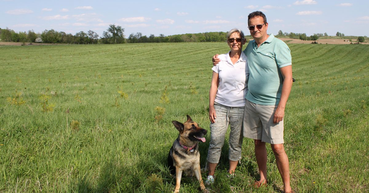 Two landowners and their dog standing on their rural property