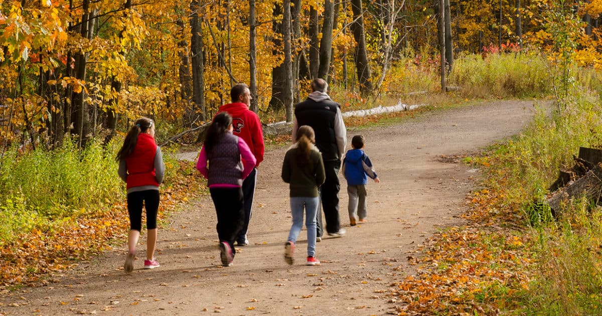 A family walks along a trail in the fall.