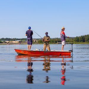 Three people standing on a boat fishing