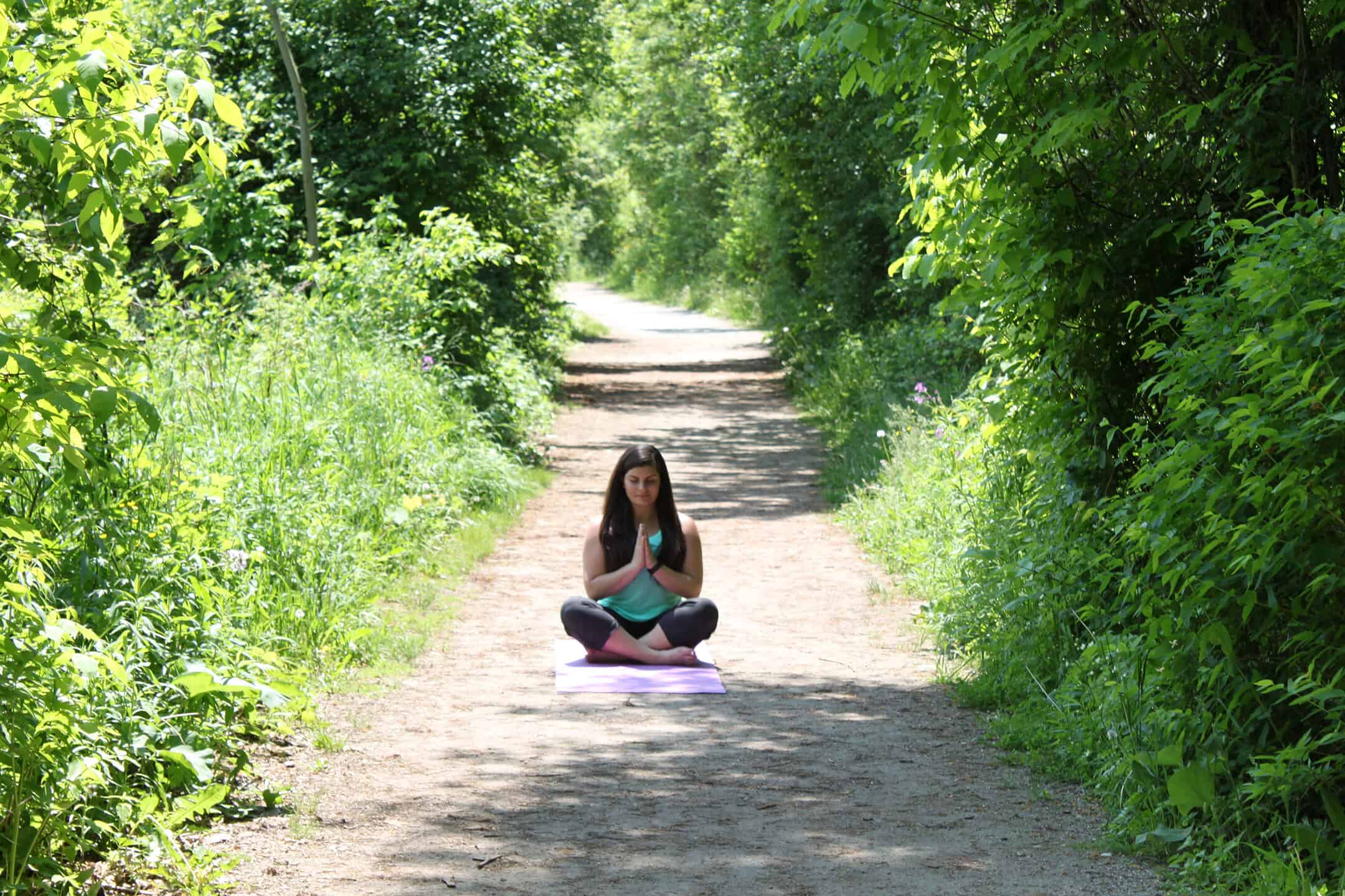 a person sitting cross-legged on a gravel path practicing meditation