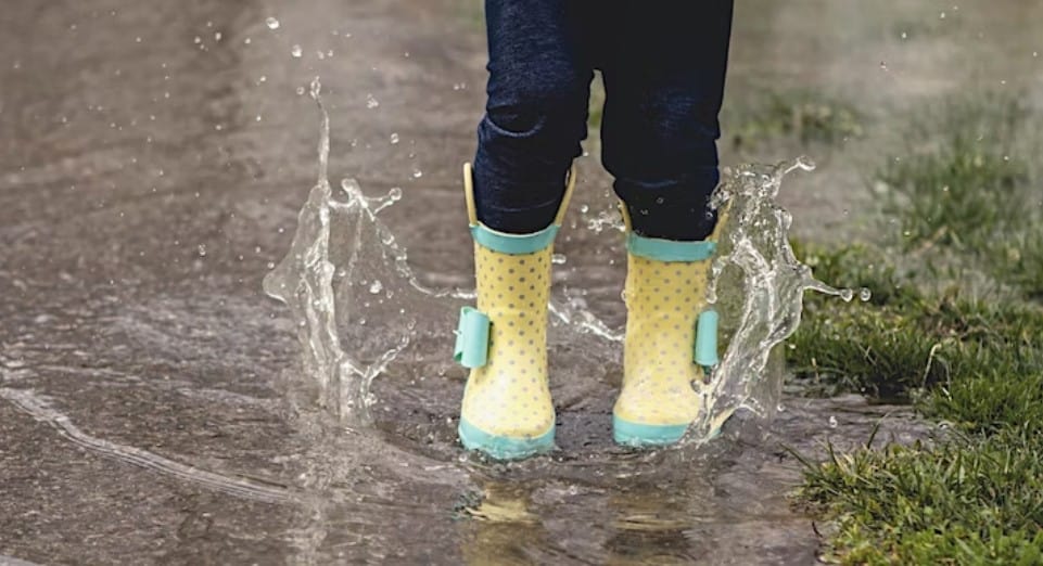Kid's rainboots splashing in puddle