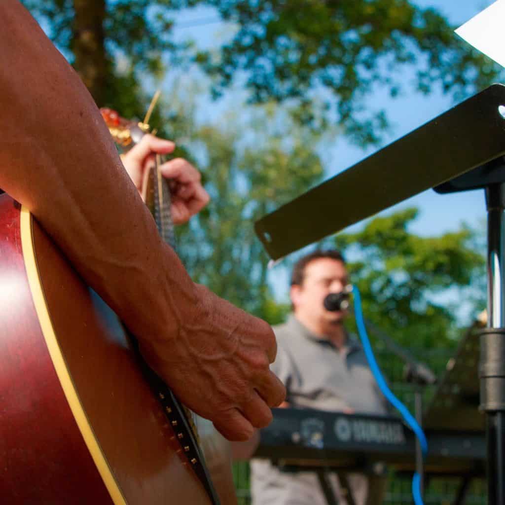 people playing a guitar and keyboard in an outdoor setting