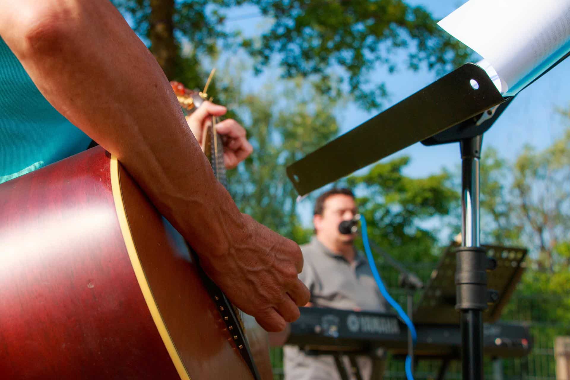 people playing a guitar and keyboard in an outdoor setting