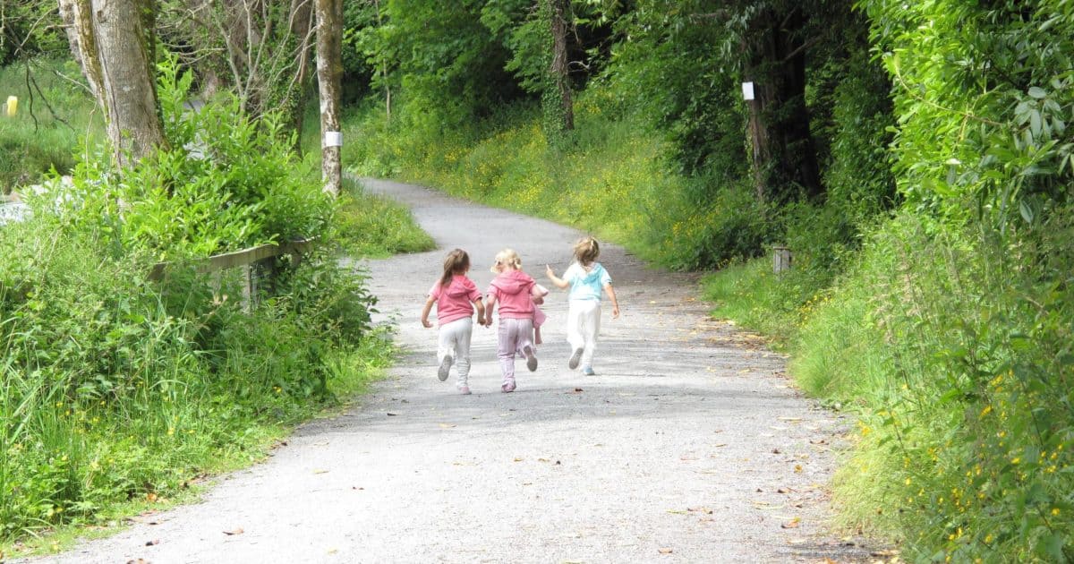 Three children running down a path
