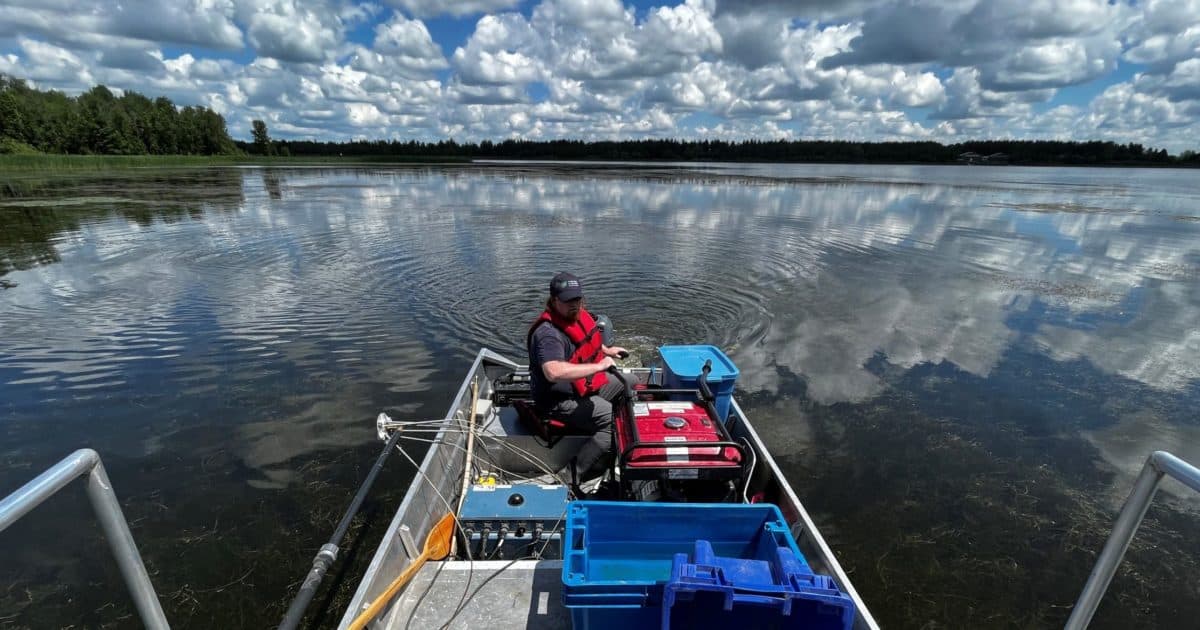 Person sitting in a boat with monitoring equipment on a lake